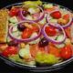 salad with cherry tomatoes, cucumbers, olives, croutons, red onion rings, and banana peppers